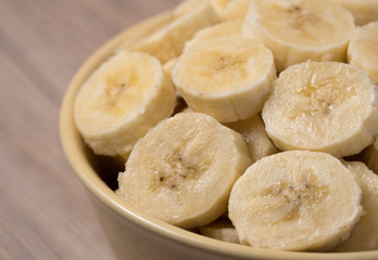 Fototapeta na wymiar Sliced banana in ceramic bowl on wooden background. Close up.