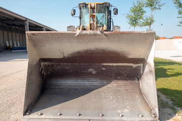 Empty tractor iron bucket, front view. Vehicle of the factory that produces the concrete