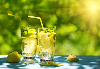 Two glasses of homemade lemonade on table under bright sun