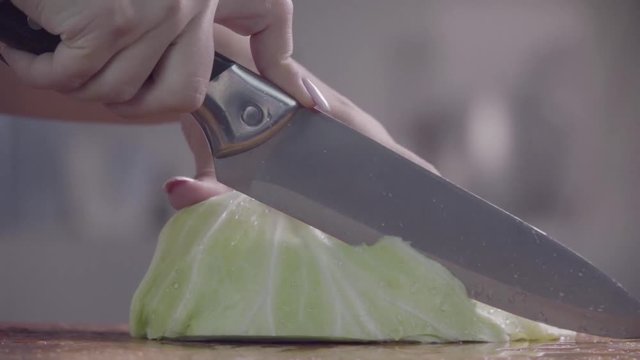 Cutting cabbage with knife on the wood. Slow motion