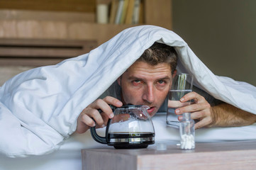 lifestyle home portrait of young exhausted and wasted man waking up suffering headache and hangover...