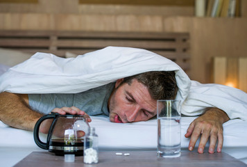 lifestyle home portrait of young exhausted and wasted man waking up suffering headache and hangover...