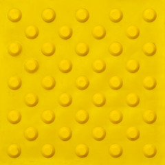 Top view of footpath tiles on a marble texture cover. Yellow circle buttons pattern. A stop signal for blind person.