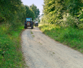 Tractor in rural area. A tractor ride on a gravel road towards cyclists, tourists.