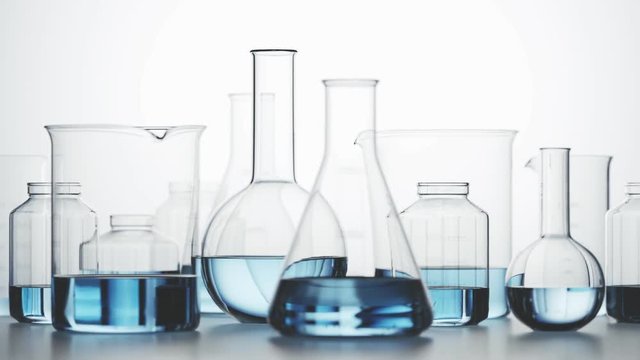 Laboratory glassware with blue liquid inside on a light background. Looping 4KHD