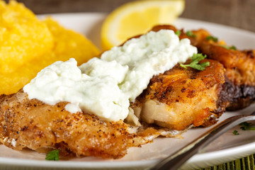 Fried fish with polenta and garlic sauce on plate