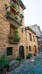 Streets with rustic houses built with stones and decorated with flowers. Mountain village.