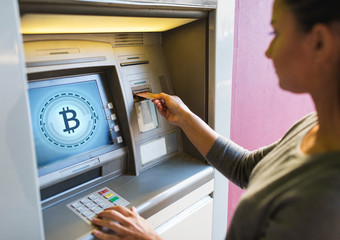finance, cryptocurrency and technology concept - close up of woman hand inserting bank card to atm...