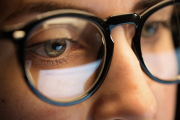 vision, business and education concept - close up of woman eyes in glasses looking at computer...