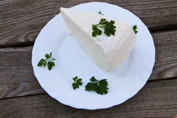 Bryndza in a plate on wooden table. Top view