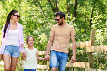 Fototapeta premium family, leisure and people concept - happy mother, father and little daughter walking in summer park