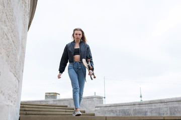 Teenage girl walking with a skate board