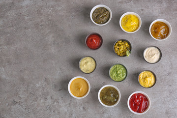 Different tasty sauces in bowls on grey table