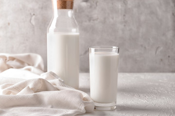 Glass and bottle of tasty milk on white table