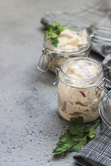 Sliced herring in sour cream sauce served in a glass jar.