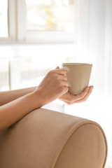 Woman holding cup of aromatic coffee at home