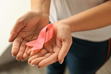Woman holding pink ribbon, closeup. Breast cancer awareness concept