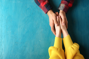 Loving young couple holding hands on color background