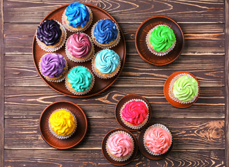 Tasty colorful cupcakes on wooden background