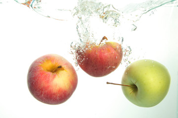 Three Apples splash in water on white