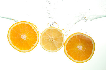 Fototapeta na wymiar Three orange slices splash of water on white