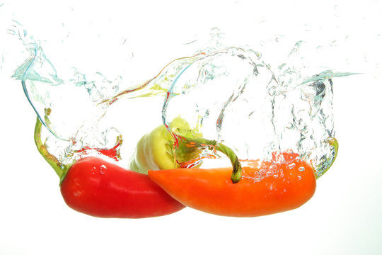 Three parika red, green and orange in water splash on white