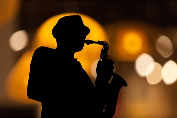Close-up man playing on saxophone on blurred background