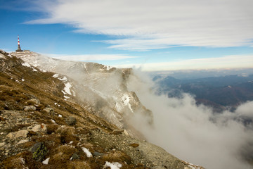 First snow on the mountains, in november, late autumn, blue sky with grey clouds
