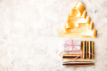 Set of professional decorative cosmetics items, makeup tools and accessories on grunged concrete backgground. Beauty & fashion present for Christmas concept. Flat lay composition, top view, copy space