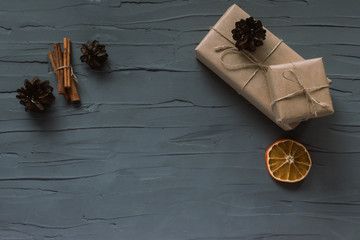 Christmas background. Top view with copyspase. Gifts wrapped in craft paper lie on a gray plaster background, cones, dried orange and cinnamon sticks
