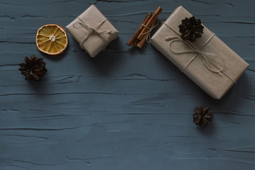 Christmas background. Top view with copyspase. Gifts wrapped in craft paper lie on a gray plaster background, cones, dried orange and cinnamon sticks