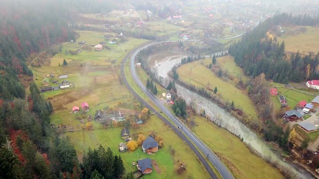 Bird's-eye view of picturesque mountain valley with a village, a railway, a road and a river. Carpathians. Ukraine
