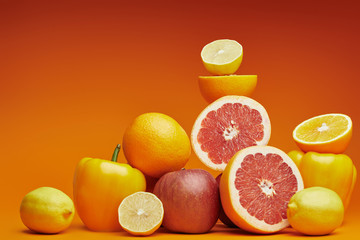 fresh ripe organic citrus fruits, apples and bell peppers on orange background