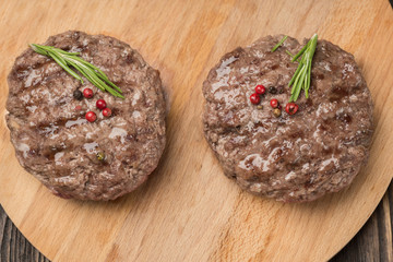 Freshly grilled burger meat ion wooden cutting board.