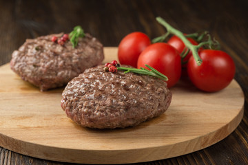 Freshly grilled burger meat ion wooden cutting board.