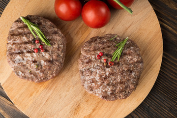Freshly grilled burger meat ion wooden cutting board.