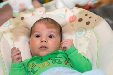 The newborn lies on swing automatic electrical chair and enjoys it