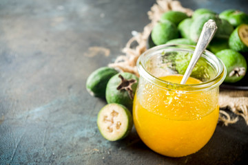 Tropical fruit preserves, homemade feijoa and lime jam on a dark blue concrete background, copy space