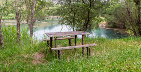 Wooden bench with a table by the lake