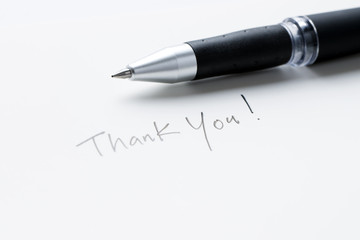 Hand writing thank you note on a piece of white paper