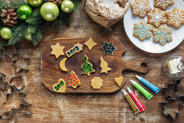 top view of arrangement of raw dough, food grade ink for christmas cookies bakery and and christmas wreath on wooden tabletop