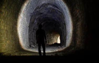 Fototapeten Man shines a lantern in an abandoned railway tunnel © ROMAN_P