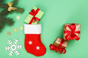 Santa's boot, gift boxes and fir tree branch on green background
