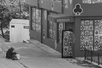 ruined adult homeless person sitting in front of casino in black white street photography in Bourgas/Bulgaria/09.03.2018/ gambling leads to addiction and bankruptcy.