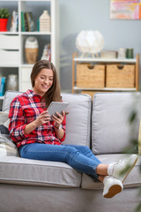 Beautiful young woman on the beige couch at home  holding tablet computer and talking skype
