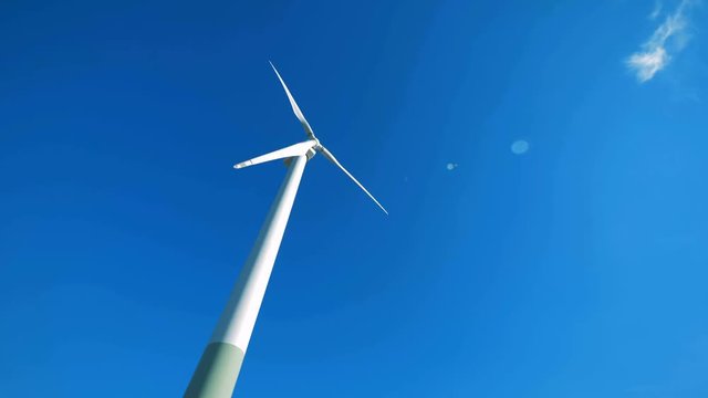 White turbine tower is rotating in the wind. Alternative energy concept.