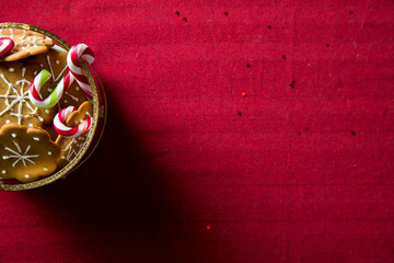 Background of gingerbread and candy cane jar and spruce branches on red table cloth. Top view. Christmas mood