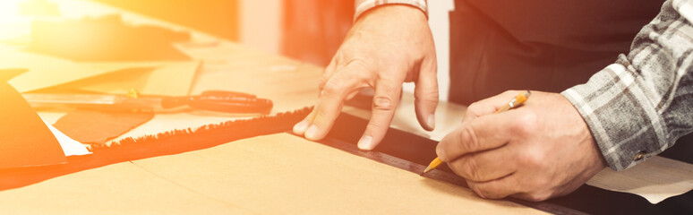 partial view of handbag craftsman making measurements by pencil and ruler in studio