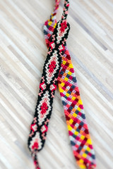 Two handmade homemade colorful natural woven bracelets of friendship isolated on light wooden background
