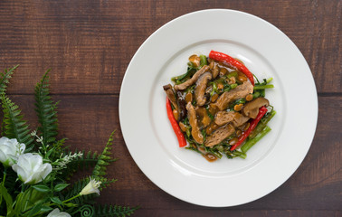 Vegetarian food,fried morning glory with mushroom,agricultural protein,red chilli and bean paste put on white ceramic plate.